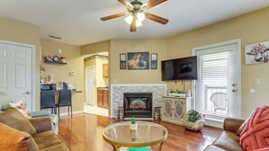 A living room with a fireplace, a ceiling fan, and a television mounted on the wall. - Walkable Retreat Near The Island! Gateway to Gsmnp (Pigeon Forge)