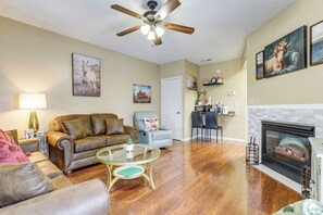 A living room with a fireplace, a ceiling fan, and a dining area. - Walkable Retreat Near The Island! Gateway to Gsmnp (Pigeon Forge)