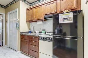 Une cuisine avec des meubles en bois, un réfrigérateur en acier inoxydable, une cuisinière et un dosseret de carrelage blanc.