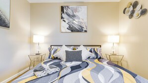 A bedroom with a bed, two bedside tables, and a wall-mounted abstract painting. - Walkable Retreat Near The Island! Gateway to Gsmnp (Pigeon Forge)