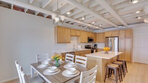 Une cuisine moderne avec des meubles en bois, un îlot central et un coin repas comprenant des chaises blanches et une table en bois.