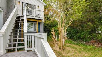 Une maison à deux étages dotée d’une terrasse en bois et d’un escalier menant à un balcon.