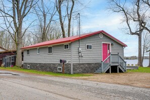A two-story building with a red roof, a stone foundation, and a small porch with a red door. - 'eagles Rest' Peaceful Cottage on Lake Champlain (Chazy)