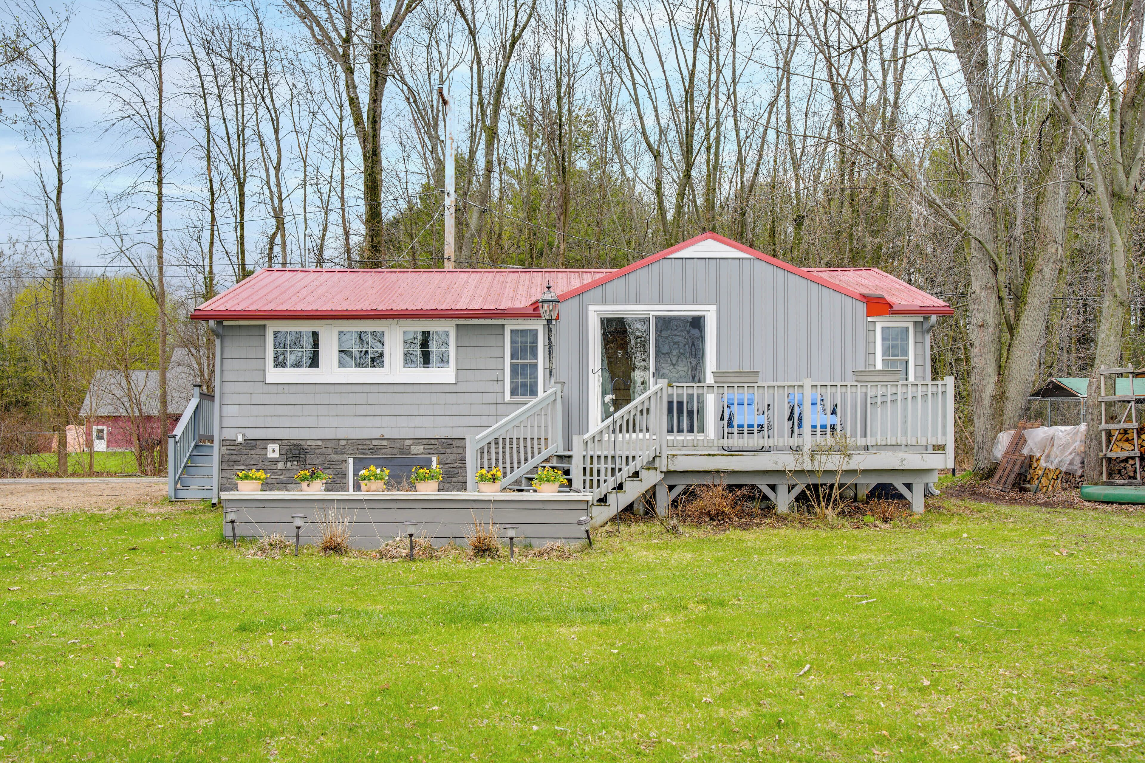 A two-story house with a red roof, a front porch, and a small deck.