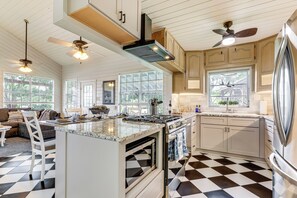 A kitchen with a checkered floor, a central island, a stove, and a refrigerator. - Lake LBJ Home: Putting Green, Pavilion & Fire Pit (Kingsland)