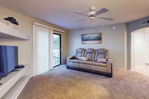 A living room with a sofa, a ceiling fan, a painting, and a television. - 2BR Condo in Fountain Hills w/ Mountain Views (Fountain Hills)