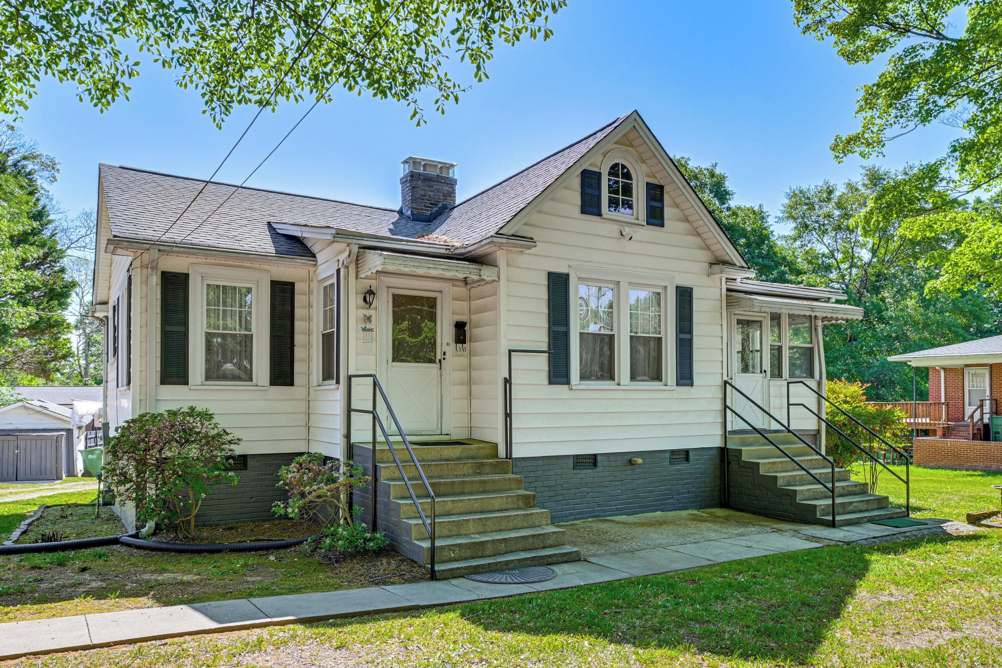 A two-story house with a front porch, a chimney, and a small front yard.