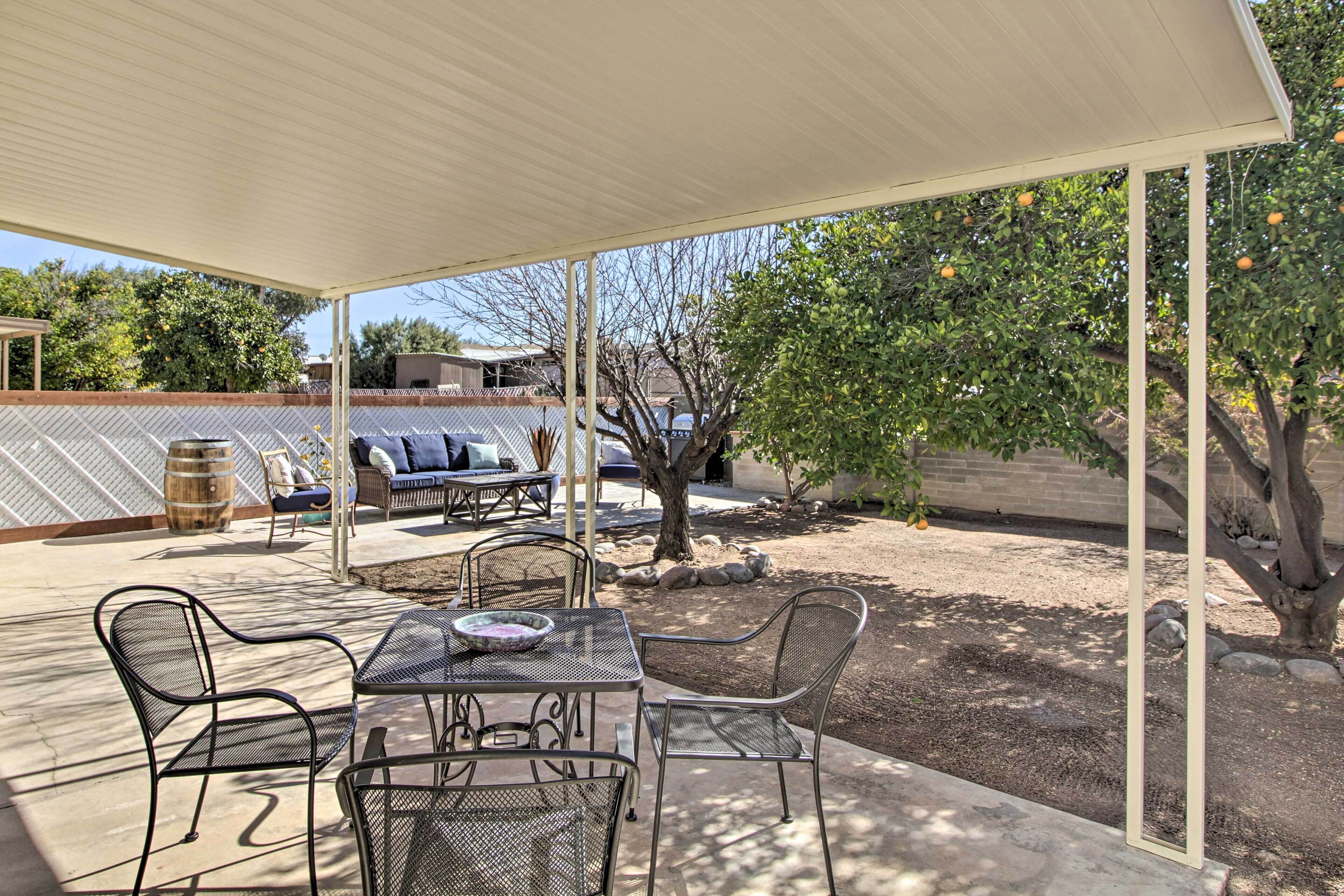 An outdoor patio with a covered seating area, a table, and chairs.