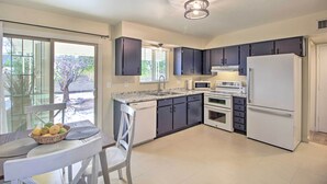 Uma cozinha moderna com armários escuros, uma geladeira branca e uma área de refeições com mesa e cadeiras.