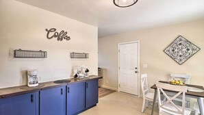 Cozinha com espaço para café, mesa de jantar com cadeiras e um detalhe decorativo na parede.