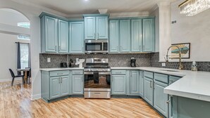 A kitchen with teal cabinets, a stainless steel oven, and a microwave.