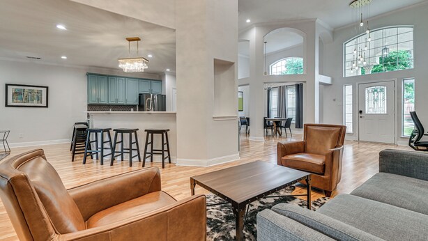 A spacious living area with leather sofas, a wooden coffee table, and a kitchen in the background.