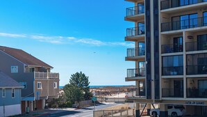 A multi-story building with balconies, a parking area, and a view of the beach. - 200 Feet to the Beach! Cute Ocean City Condo (Ocean City)