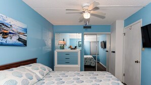 A bedroom with a bed, a dresser, a mirror, a ceiling fan, and a door. - 200 Feet to the Beach! Cute Ocean City Condo (Ocean City)