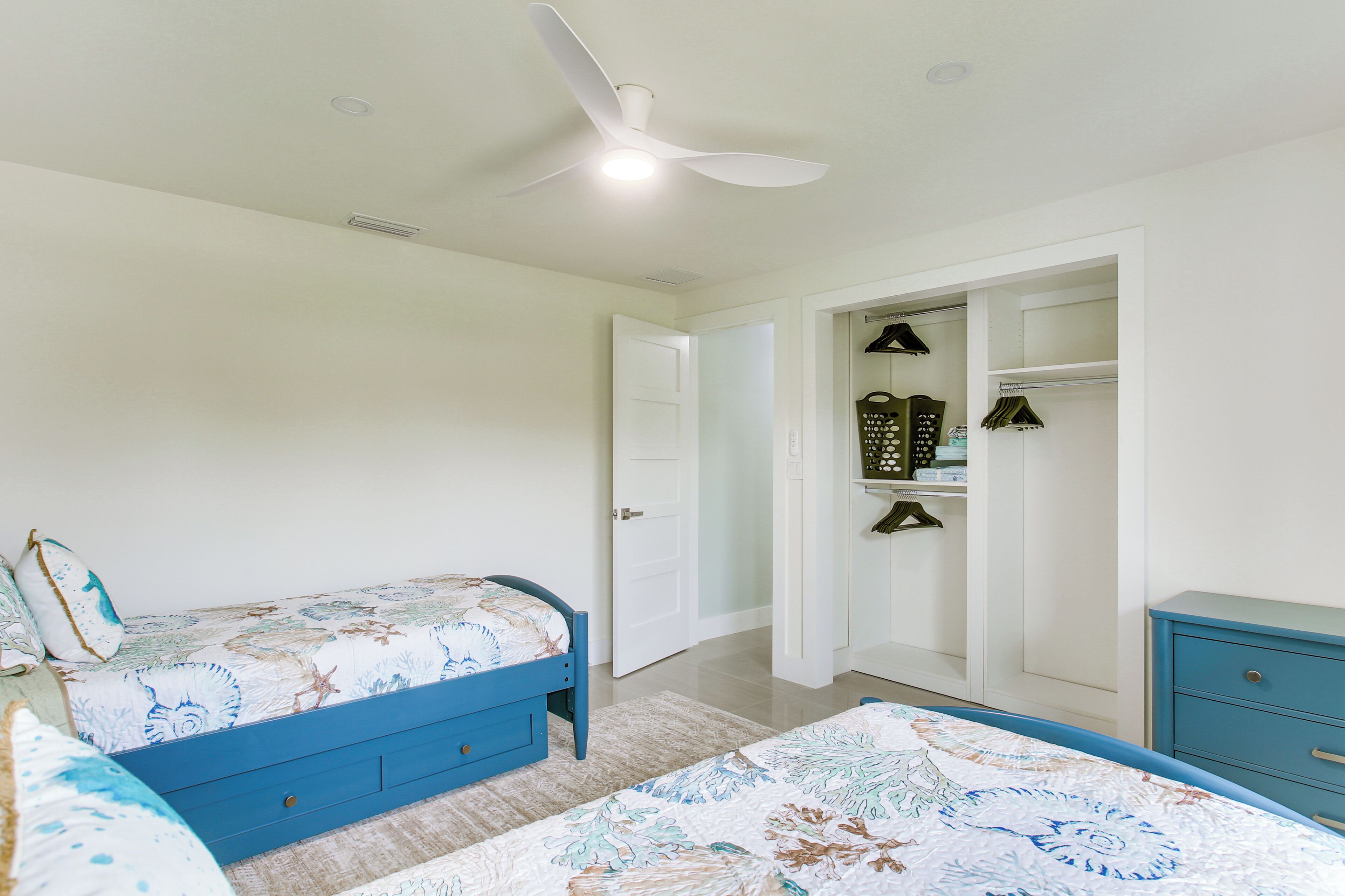 A bedroom with a bed, a dresser, a closet, and a ceiling fan.