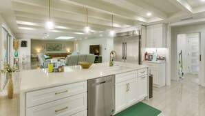 A modern kitchen with white cabinetry, stainless steel appliances, and pendant lighting. - Luxe Canal Home 2 King Suites Huge Salt Pool (Punta Gorda)