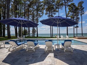 A poolside area with lounge chairs and umbrellas, surrounded by tall trees and a view of the ocean. - Bayview 2.0 | an ESVR property (Wittman)