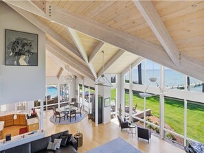 A spacious living area with a high ceiling, large windows, and a view of the sea. - Bayview 2.0 | an ESVR property (Wittman)