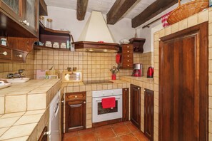 Eine Küche mit Holzausstattung, einer gefliesten Spritzschutzleiste, einem Einbauofen und einer Kaffeemaschine.