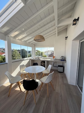 A modern kitchen with a dining area, large windows, and a view of the city.