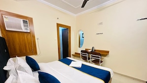 Een hotelkamer met een bed, een bureau, een stoel, een airco en een deur.