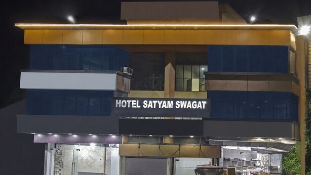 Een meerlaags gebouw met een bord waarop 'HOTEL SATYAM SWAGAT' staat.