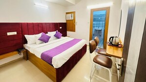 Een hotelkamer met een bed, een bureau, een stoel, een airconditioner en een plafondventilator.