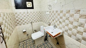 Een badkamer met toilet, wastafel en betegelde wanden.