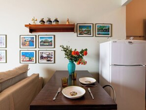 Un comedor con una mesa dispuesta para dos, un florero y un refrigerador.