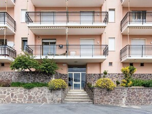 Un edificio de varios pisos con balcones, fachada de piedra y una puerta que indica 'condominio Le ROSES'.