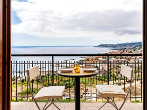 Un balcón con mesa y sillas, con vista a un paisaje urbano costero.