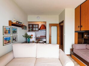 Un espacio habitable compacto con sofá, una mesa de comedor, una zona de cocina y un armario de madera.