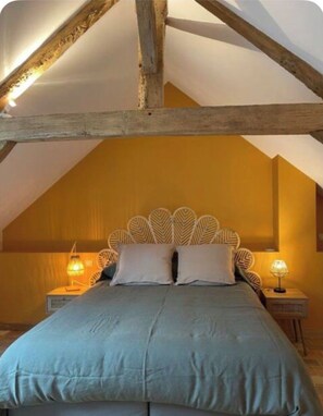 A bedroom with a sloped ceiling, a bed with a headboard, two bedside lamps, and a nightstand. - MAISON, on the banks of the Loire, a quarter of an hour from Saumur. (Varennes Sur Loire)