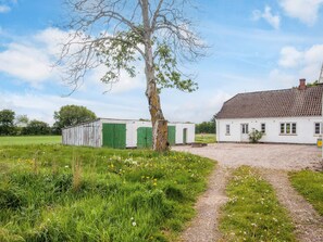 A rural property with a gravel path leading to a white house with a tiled roof, surrounded by green fields and a large tree. - 6 Person Holiday Home in Rodding (Rodding)