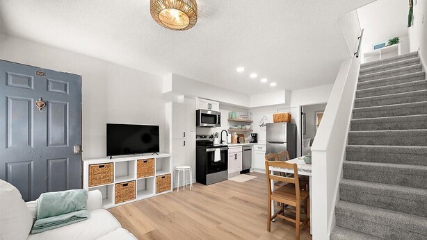 Um interior moderno com sala de estar, cozinha e escadaria.