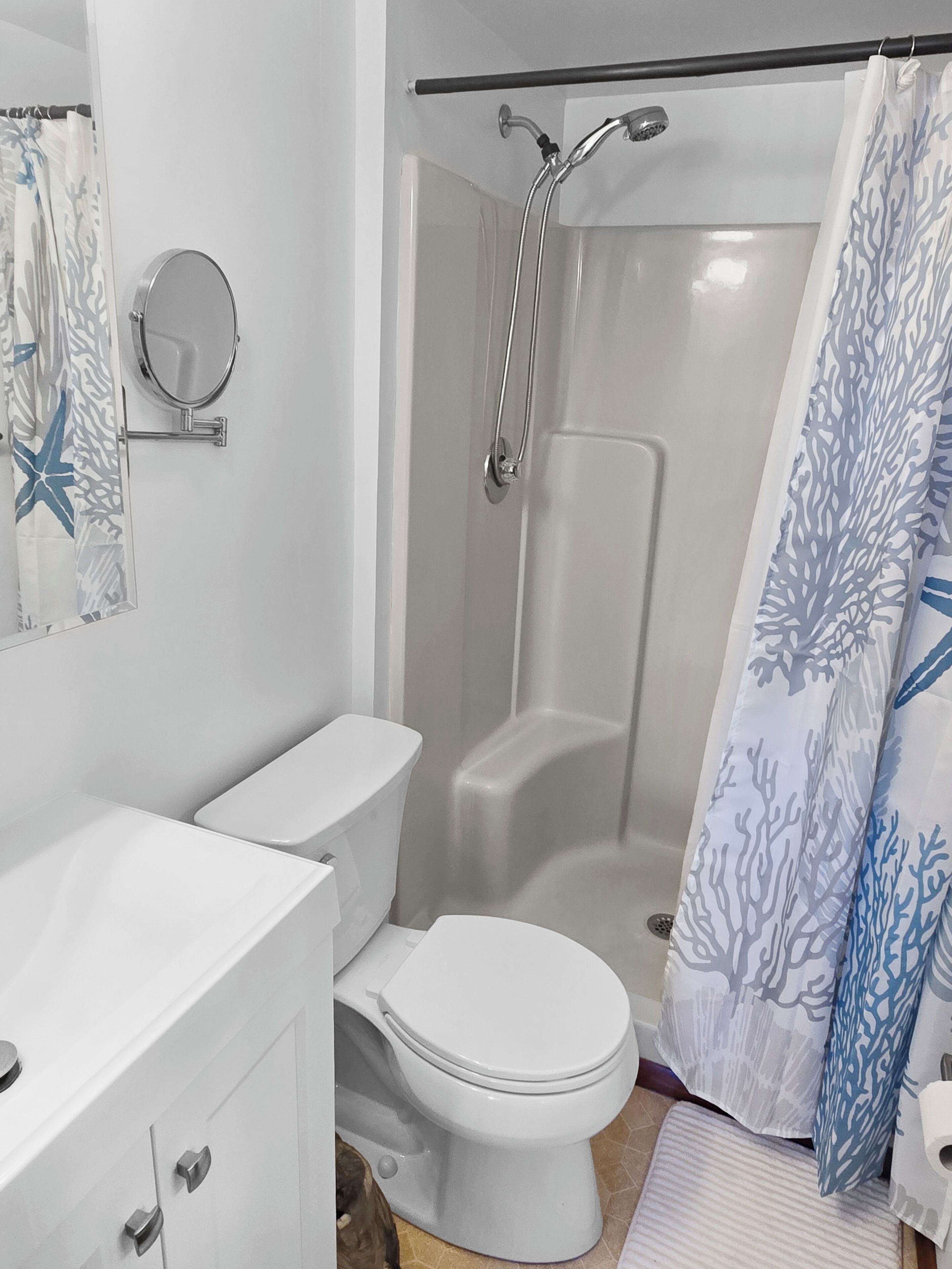 A bathroom with a toilet, a shower, a mirror, and a towel rack.