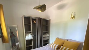 A bedroom with a bed, a wardrobe, a mirror, and a light fixture.