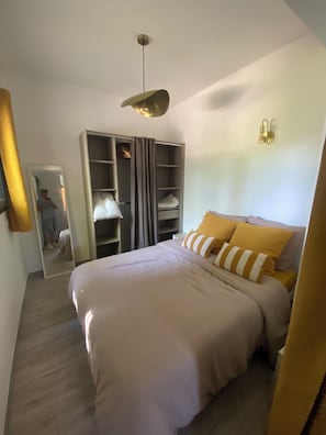 A bedroom with a bed, a wardrobe, a mirror, and a light fixture.
