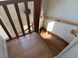 A wooden staircase with a handrail, a white wall, and a small shelf. - Exceptional villa with sea view-Luxurious ambience (Saint-Côme-de-Fresné)