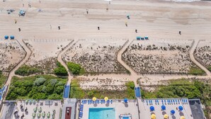 An aerial view of a beach with a pool area, including sun loungers and umbrellas. - Plaza 1612 2bd Oceanfront condo (Ocean City)