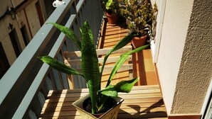 A wooden balcony with a potted plant and a small table. - Elsi's Place (Premià de Mar)