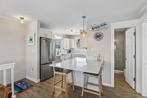 A modern kitchen with a central island, stainless steel appliances, and a sign indicating fresh daily seafood. - The Blue Crab Cottage -- Back for 2026 Pool, Hot Tub and More! (Duck)