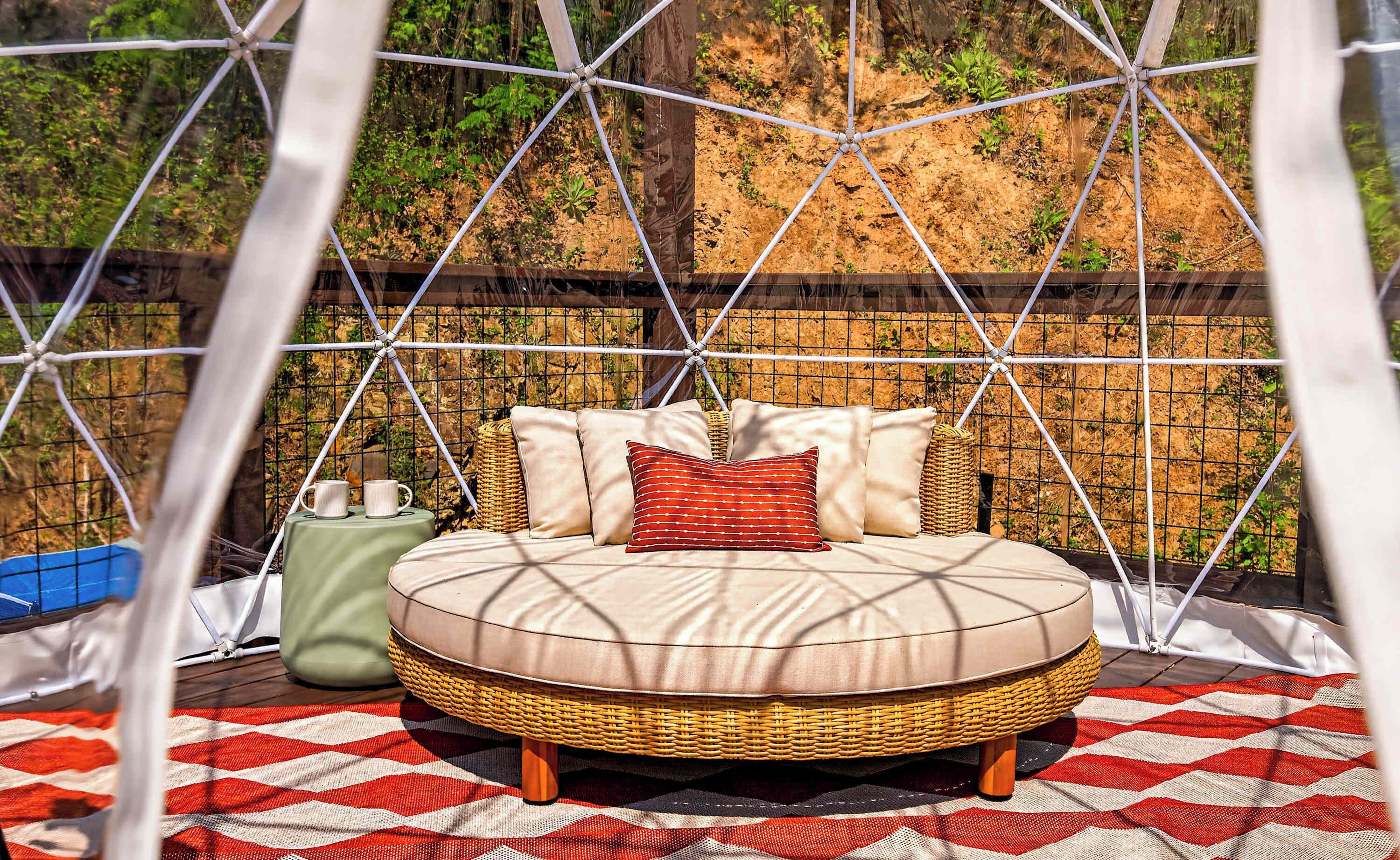 Una cama con estructura de mimbre, manta a cuadros y pared con diseño de cuadrícula.