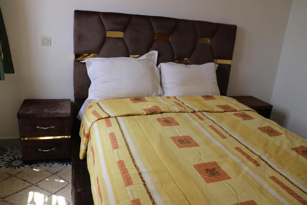 Ein Bett mit einem gemusterten Überwurf, einem Kopfteil und zwei Nachttischen mit Schubladen.