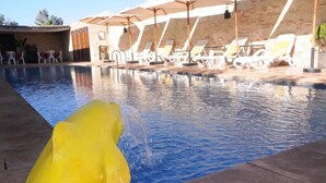 A swimming pool with lounge chairs and umbrellas, a brick wall, and a concrete deck. - Dar Margoum (Chwiter)