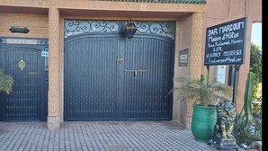 A large, ornate black gate with a signboard to the right. - Dar Margoum (Chwiter)