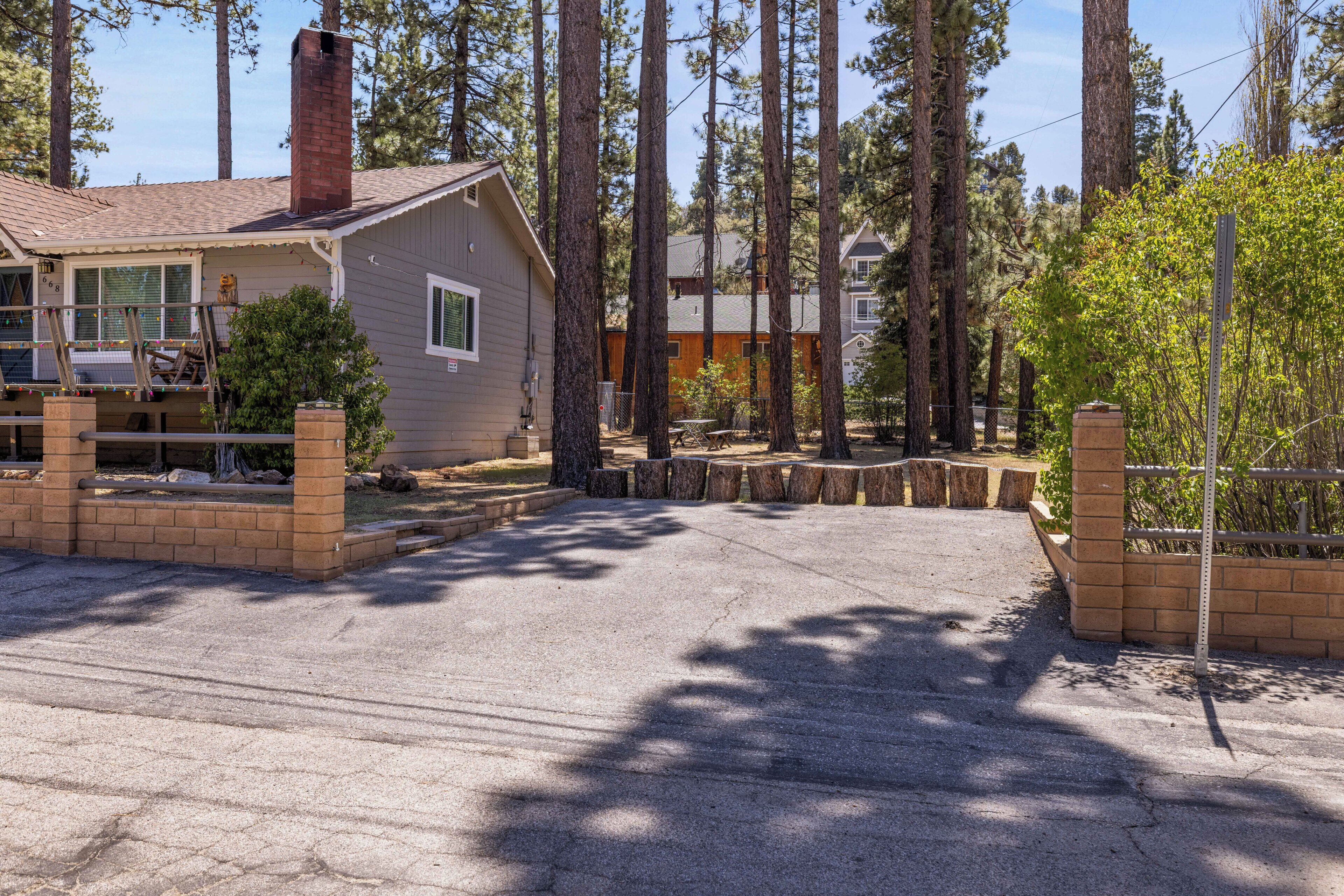 A residential area with a house, a paved driveway, and tall trees.