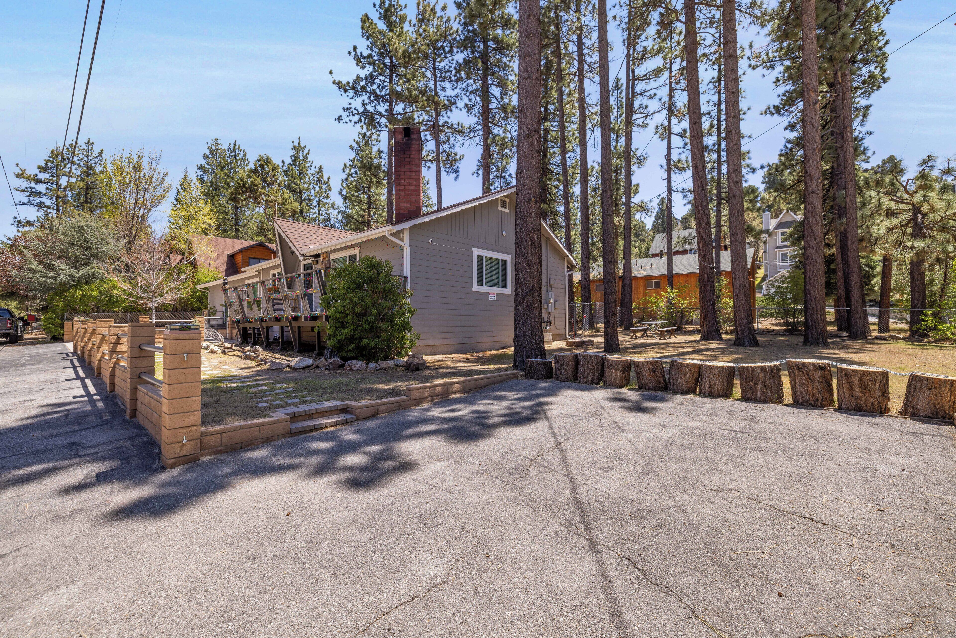 A two-story house with a chimney, surrounded by tall pine trees.