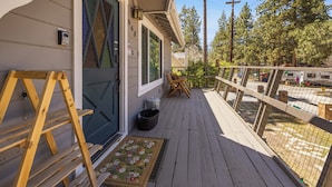 A wooden deck with a metal railing, a door with a number, and a mailbox. - Cozy Bear Lodge (Big Bear City)
