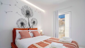 Un dormitorio moderno con una cama grande, vistas al exterior y cuadros en la pared.